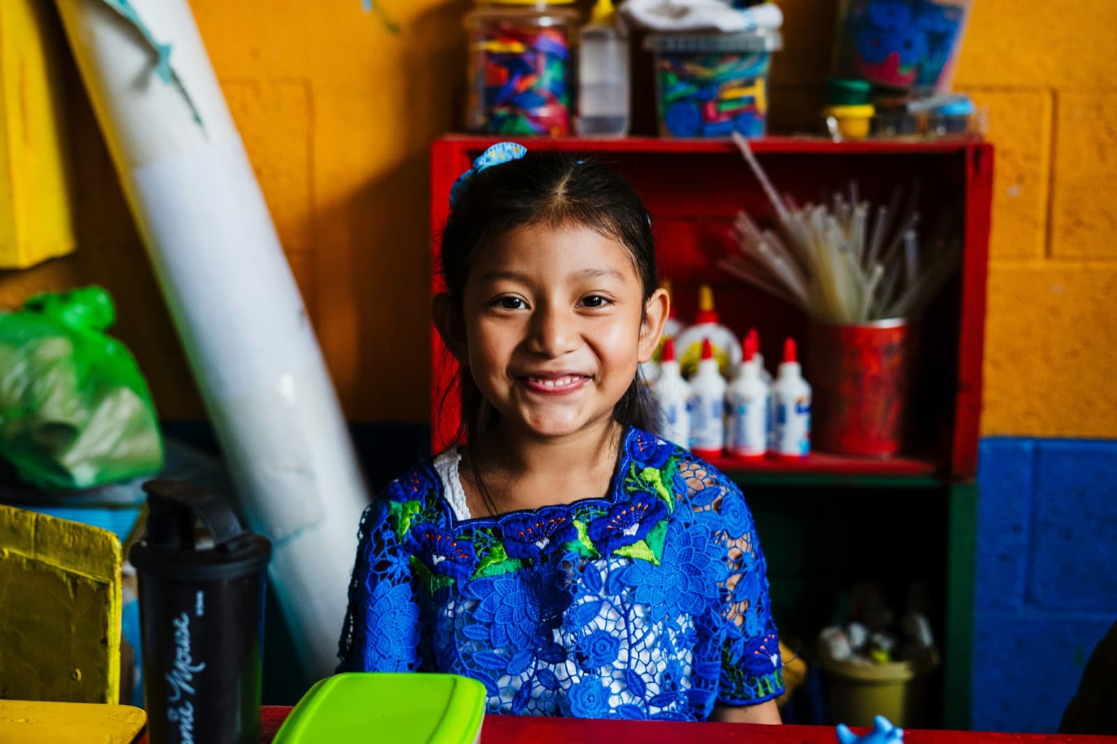 A young student from San Jacinto, Guatemala smiling at her desk in a classroom